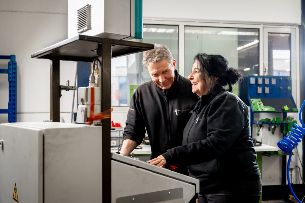 Twee mensen werken samen aan een machine.