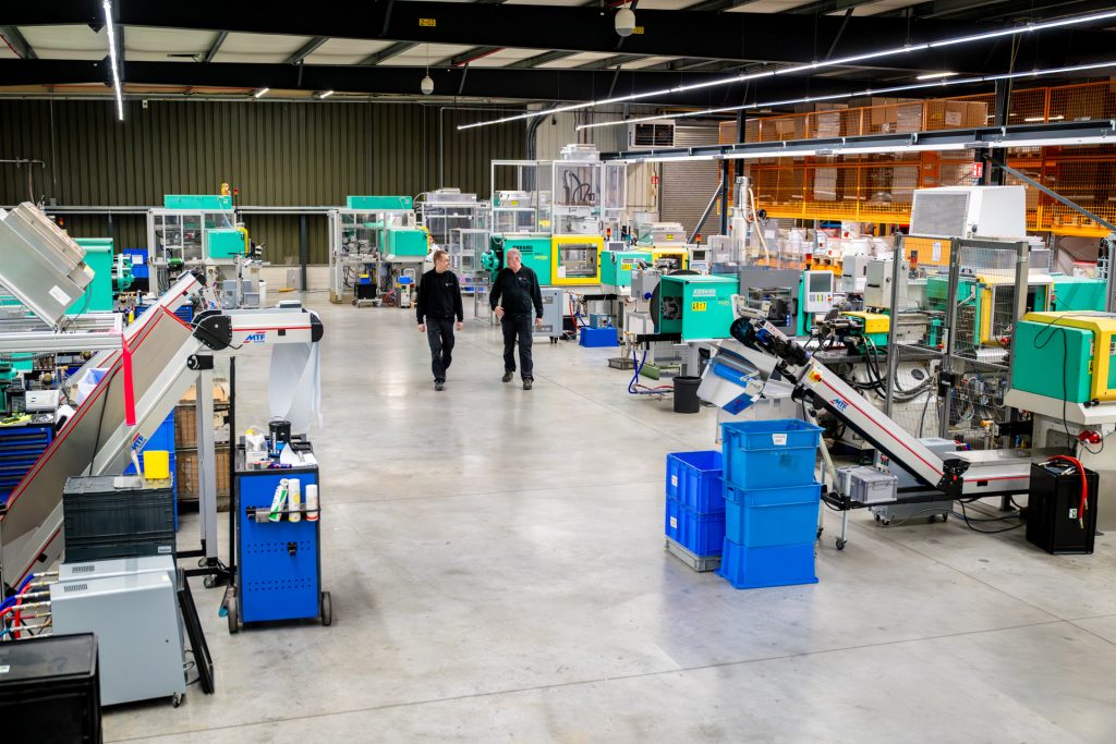 Moderne fabriekshal met machines en werkers.