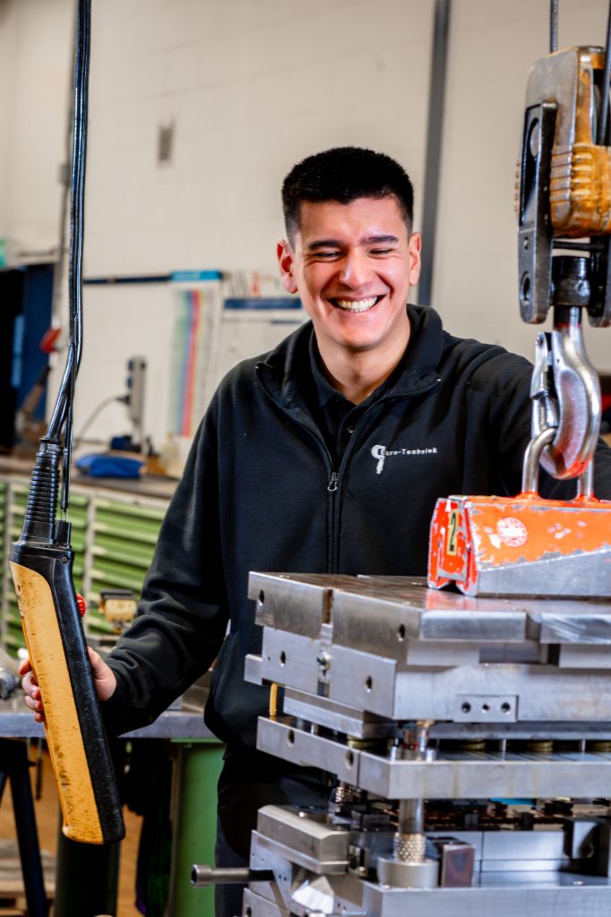 Lachende man in fabriek naast machine